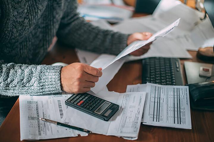 Man looking through paperwork with calculator