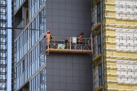 Construction workers on a high rise building replacing cladding