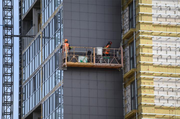 Construction workers on a high rise building replacing cladding