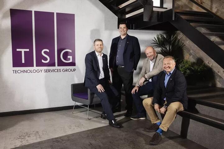 Four men in front of a purple logo that says TSG