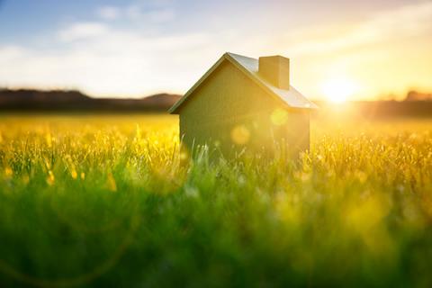 House in a field with the sun setting behind it