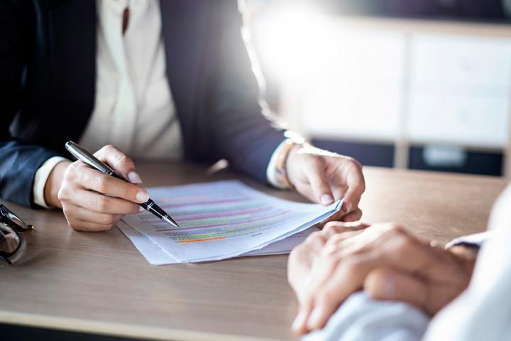 Close up of two people reviewing a document, one person holding a pen