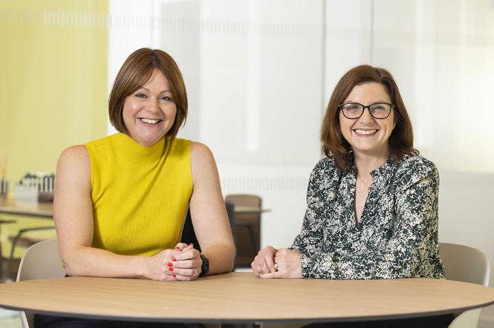 Kelly Jordan and Louise Duffy sitting at a table and smiling at the camera