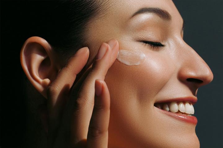 Close up of a profile of woman's face applying cream to the face