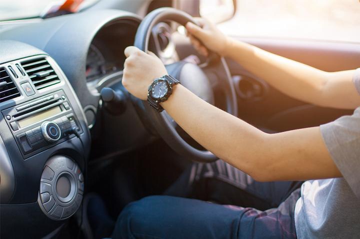 A man with both hands of the steering wheel inside a car