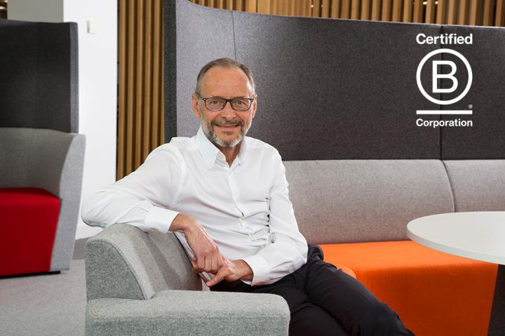 hugh welch sitting on an orange sofa with his arm over the back