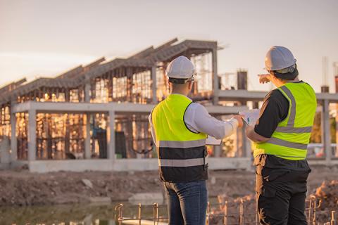 A pair of construction workers collaborating on a large-scale building project 