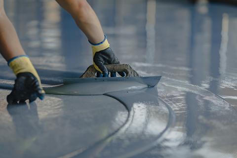 Resin flooring being finished by a construction worker